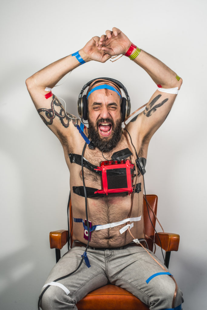 Jonny cheering topless with sound equipment taped to him