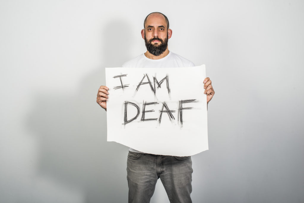 Jonny holding a sign saying 'I AM DEAF'